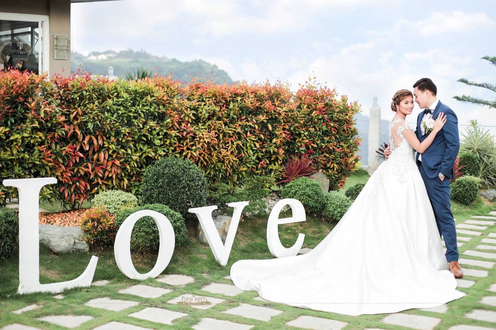 A real couple posed with a garden Love marquee sign